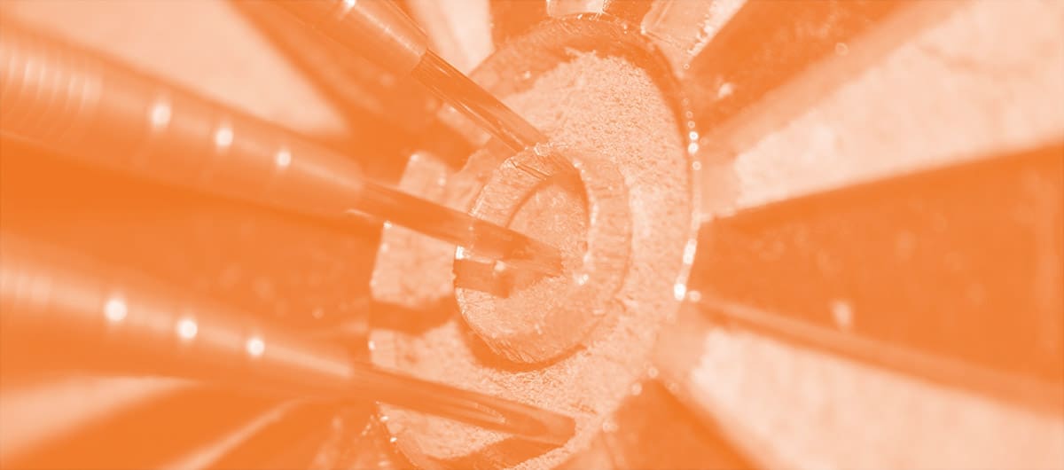 Close-up view of 3 darts wedged into the bullseye of a dart board