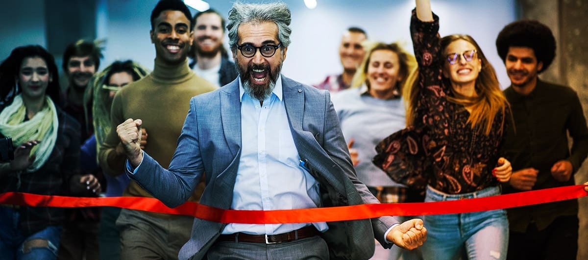 Group of people celebrating and running through a red ribbon