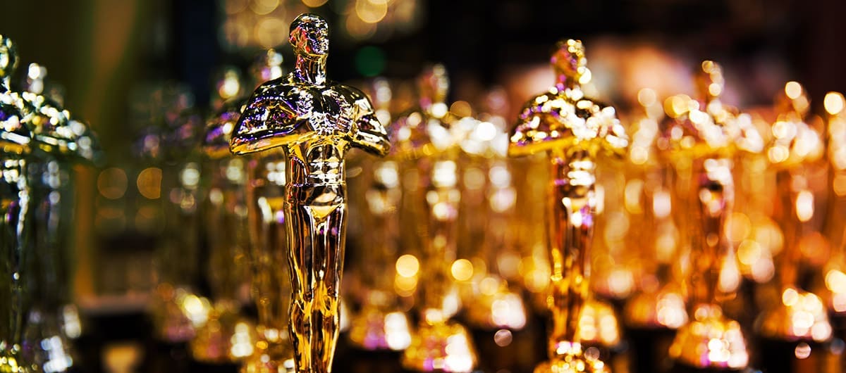 A group of gold-plated, muscular man trophies with a clear focus on one trophy