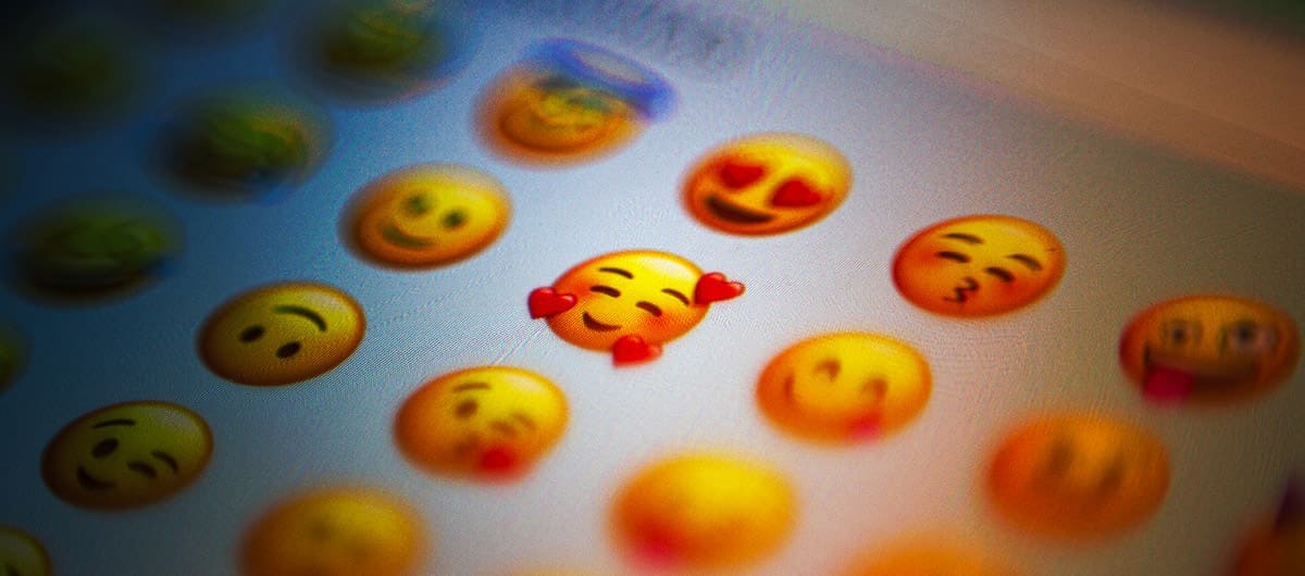 Emoji keyboard, focusing on the blushing hearts smiley face with the rest of the image being blurred