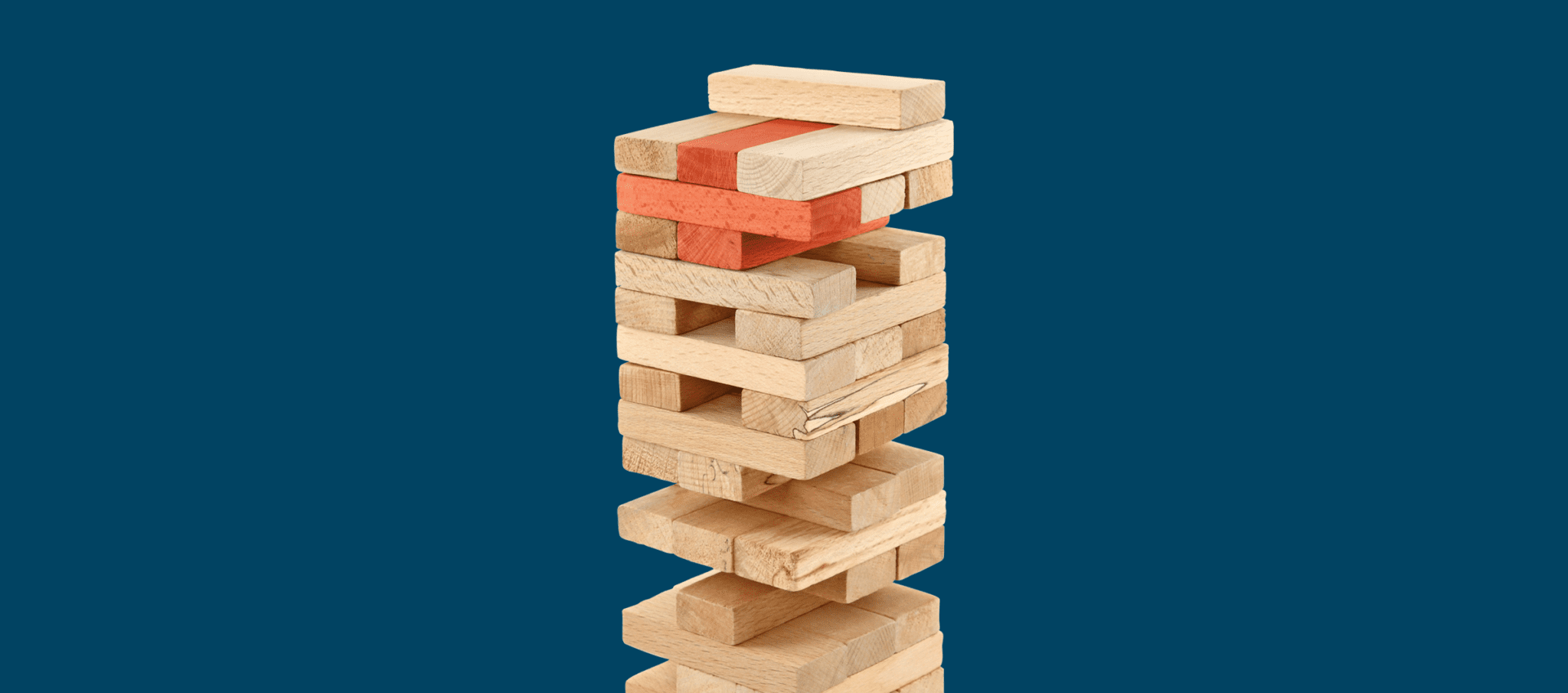 A half-played jenga game with 3 red pieces making a plus sign