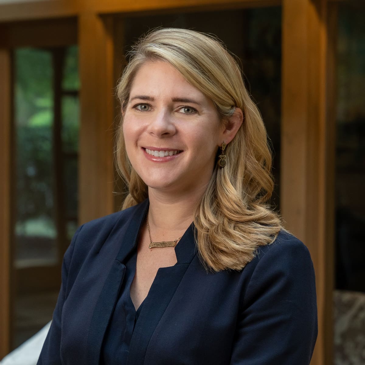 Headshot of a smiling woman with blonde hair dressed in corporate attire in front of a blurred background