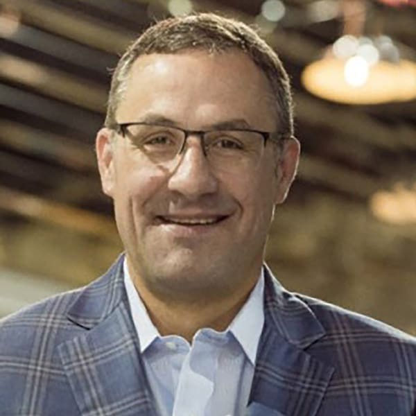 Up close headshot of a smiling man with light hair dressed in a blazer